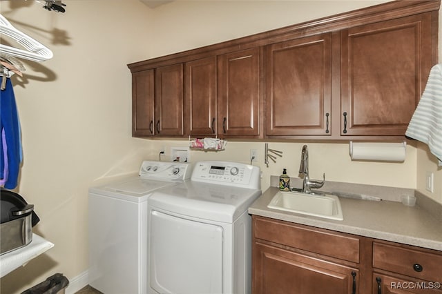 clothes washing area featuring washer and clothes dryer, sink, and cabinets