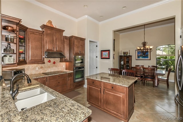 kitchen with light stone countertops, sink, hanging light fixtures, an inviting chandelier, and black electric stovetop