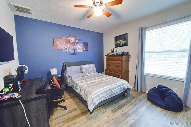 bedroom featuring a textured ceiling, ceiling fan, wood finished floors, and visible vents