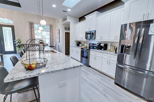 kitchen featuring stainless steel appliances, tasteful backsplash, a kitchen island with sink, white cabinets, and a sink