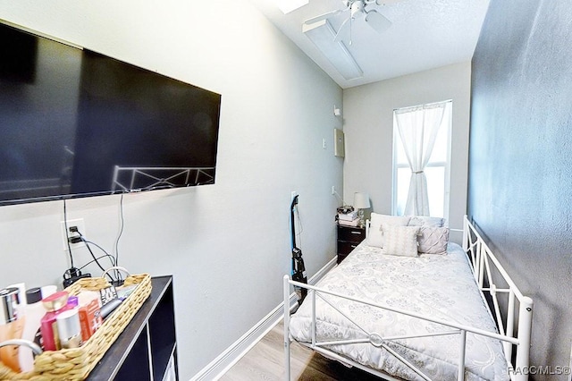 bedroom with a ceiling fan, vaulted ceiling, baseboards, and wood finished floors