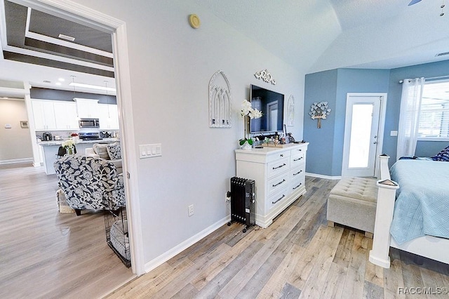 bedroom featuring light wood-type flooring, visible vents, baseboards, and vaulted ceiling