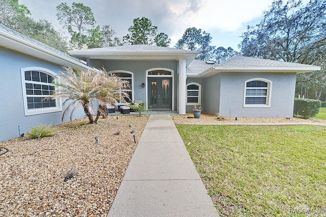 ranch-style home with a shingled roof, french doors, a front lawn, and stucco siding