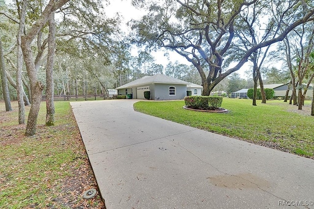 view of property exterior featuring a garage, fence, a yard, driveway, and stucco siding