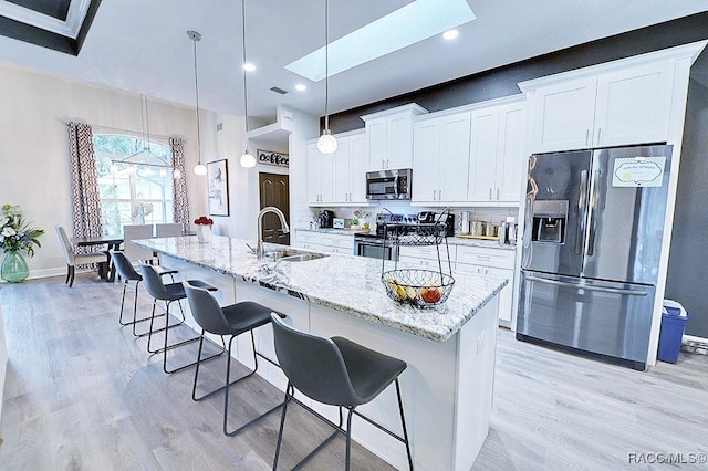 kitchen featuring a kitchen bar, light stone counters, stainless steel appliances, and a sink