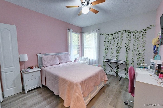 bedroom featuring light wood-type flooring, a textured ceiling, and a ceiling fan