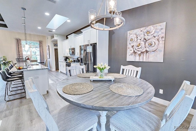 dining area with a skylight, baseboards, light wood-type flooring, a notable chandelier, and recessed lighting