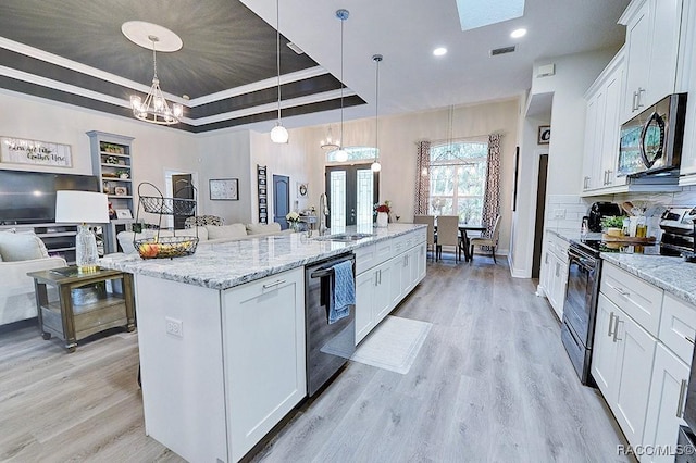 kitchen featuring black electric range, a raised ceiling, stainless steel microwave, a sink, and dishwashing machine