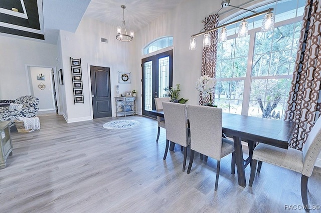 dining space featuring a notable chandelier, a high ceiling, baseboards, and wood finished floors