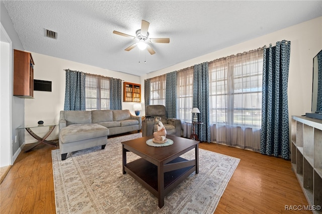 living room with a textured ceiling, hardwood / wood-style flooring, and ceiling fan