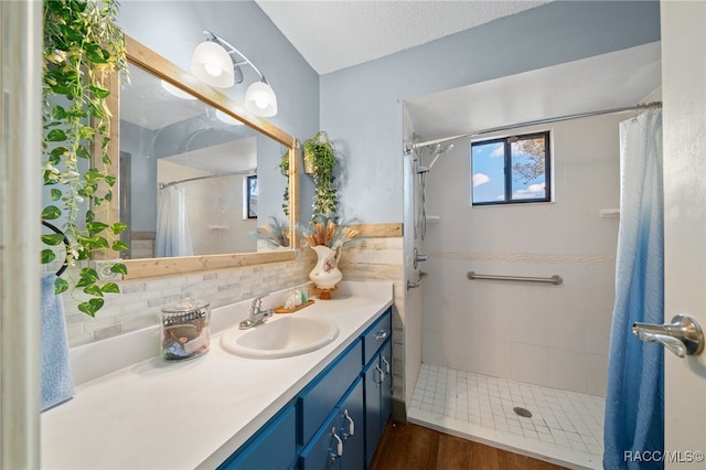 bathroom with curtained shower, hardwood / wood-style floors, a textured ceiling, decorative backsplash, and vanity