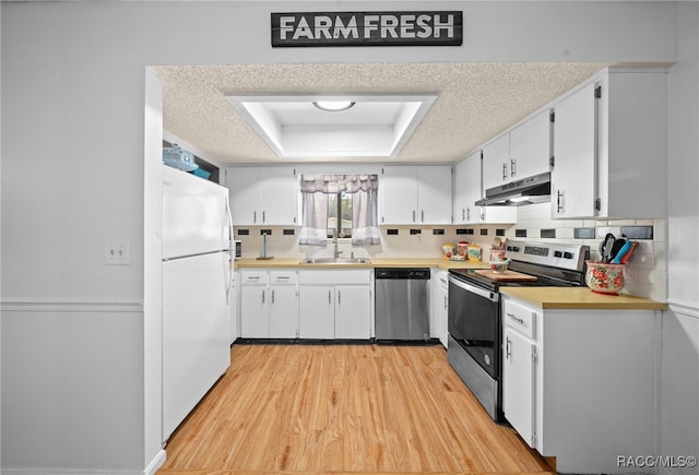 kitchen featuring a raised ceiling, light wood-type flooring, a textured ceiling, and appliances with stainless steel finishes