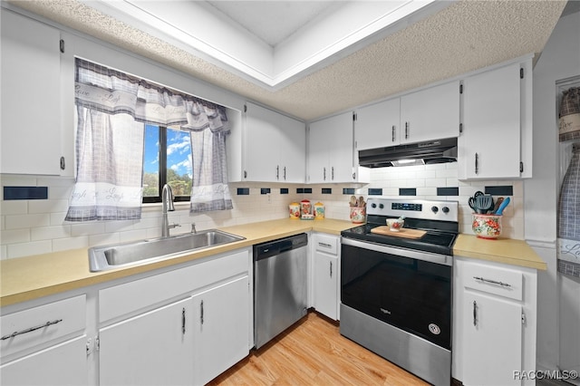 kitchen with backsplash, stainless steel appliances, sink, light hardwood / wood-style flooring, and white cabinets