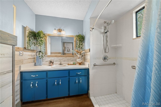 bathroom featuring vanity, a textured ceiling, wood-type flooring, tile walls, and curtained shower