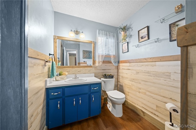 bathroom featuring vanity, wood walls, toilet, a textured ceiling, and wood-type flooring