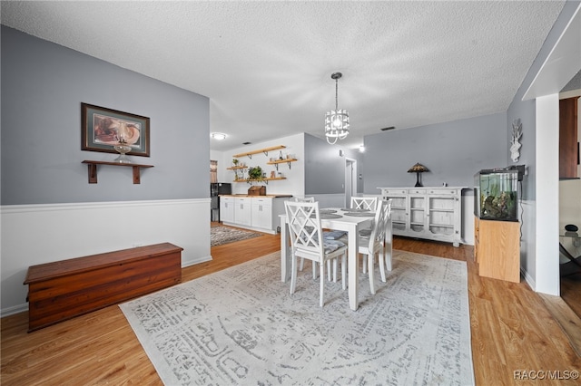 dining area featuring a chandelier, a textured ceiling, and light hardwood / wood-style flooring