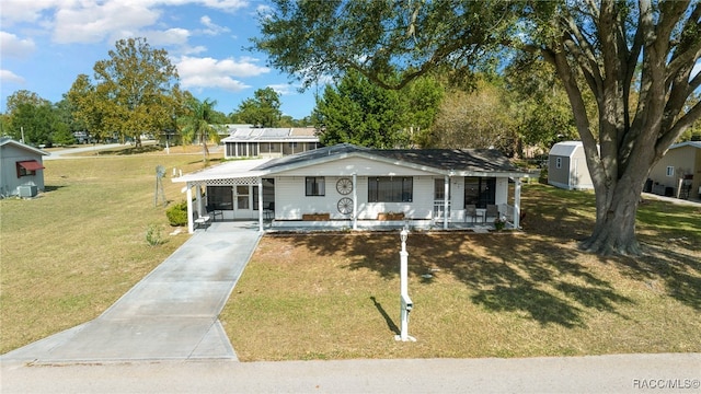 view of front facade featuring a front lawn, covered porch, and a shed