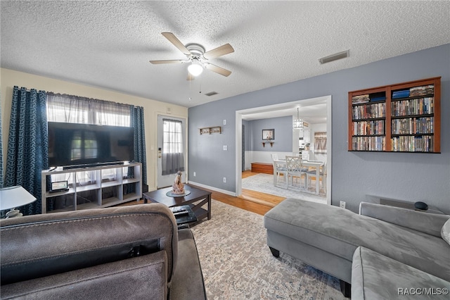 living room with a textured ceiling, hardwood / wood-style flooring, and ceiling fan