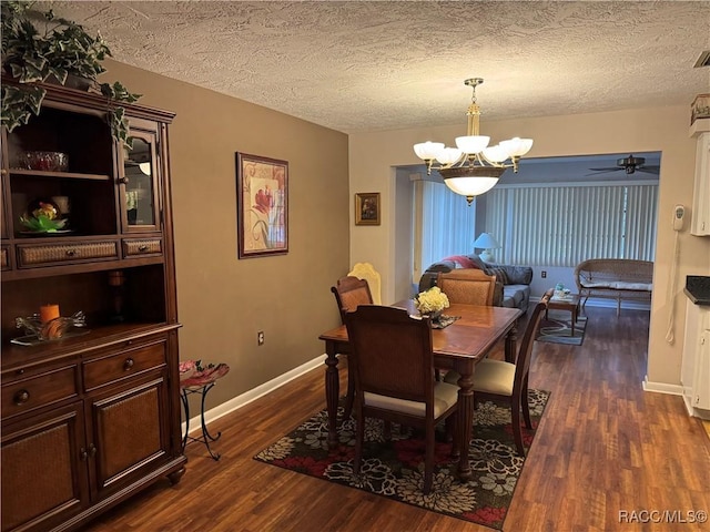 dining room with dark wood-style flooring, a textured ceiling, baseboards, and an inviting chandelier