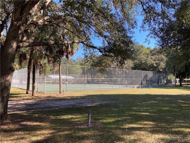 view of community featuring a yard, a tennis court, and fence