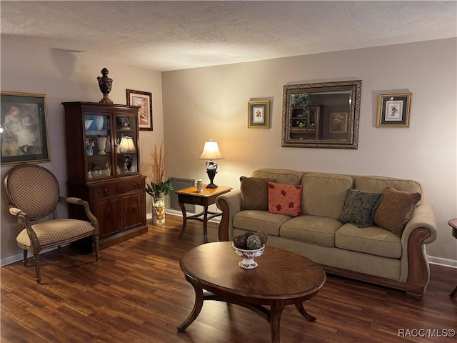 living area featuring a textured ceiling, dark wood-style flooring, visible vents, and baseboards