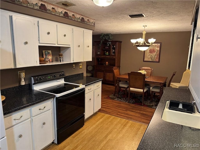 kitchen featuring dark countertops, white cabinets, black range with electric stovetop, and hanging light fixtures