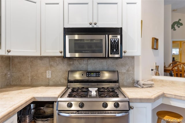 kitchen with white cabinets, appliances with stainless steel finishes, and backsplash