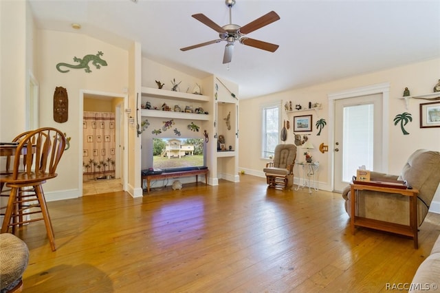 sitting room with built in features, hardwood / wood-style flooring, vaulted ceiling, and ceiling fan