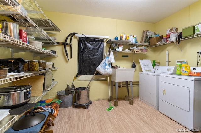 laundry area featuring light wood-type flooring, separate washer and dryer, and sink