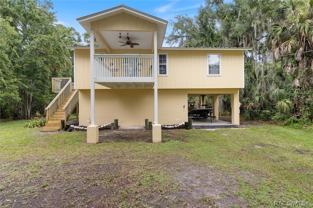 rear view of property featuring a lawn and ceiling fan