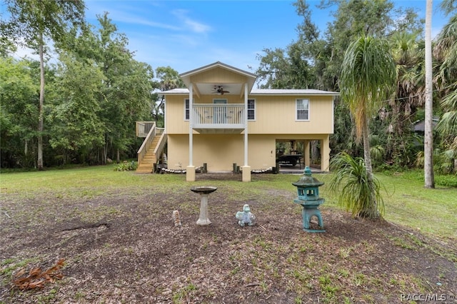 back of house featuring a carport, ceiling fan, and a lawn