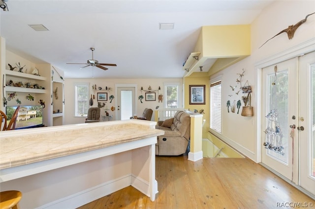 kitchen with a wealth of natural light, tile counters, ceiling fan, and light hardwood / wood-style flooring