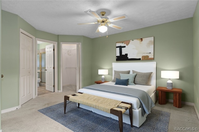 carpeted bedroom with ensuite bath, a textured ceiling, ceiling fan, a spacious closet, and a closet