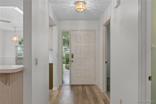 foyer entrance featuring a textured ceiling, light wood-type flooring, and plenty of natural light