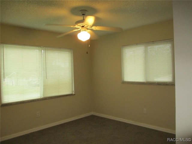 unfurnished room with dark carpet, a textured ceiling, baseboards, and ceiling fan