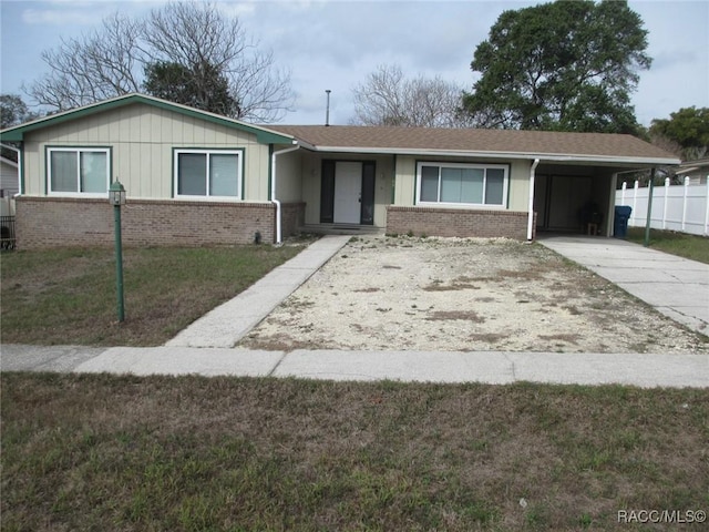 ranch-style house with driveway, a front yard, a carport, and brick siding