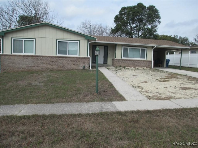 ranch-style house with driveway, a front yard, an attached carport, and brick siding