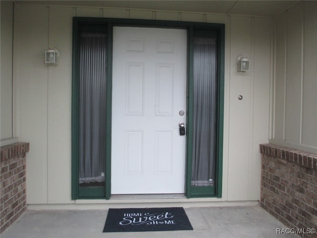 property entrance featuring board and batten siding and brick siding