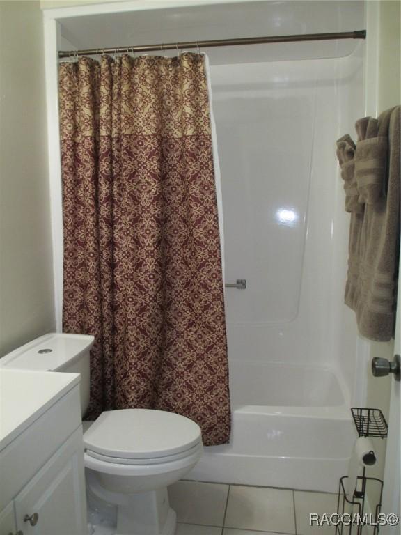 bathroom featuring toilet, shower / bath combo, vanity, and tile patterned floors