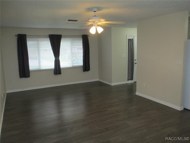 empty room with dark wood finished floors, visible vents, ceiling fan, a textured ceiling, and baseboards