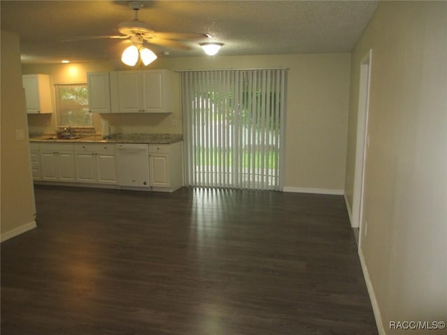 kitchen featuring dark wood-style floors, baseboards, white dishwasher, and white cabinetry