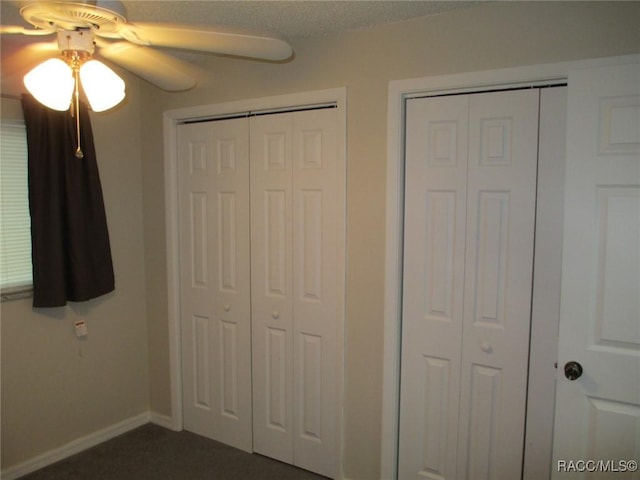 unfurnished bedroom featuring ceiling fan, baseboards, and multiple closets