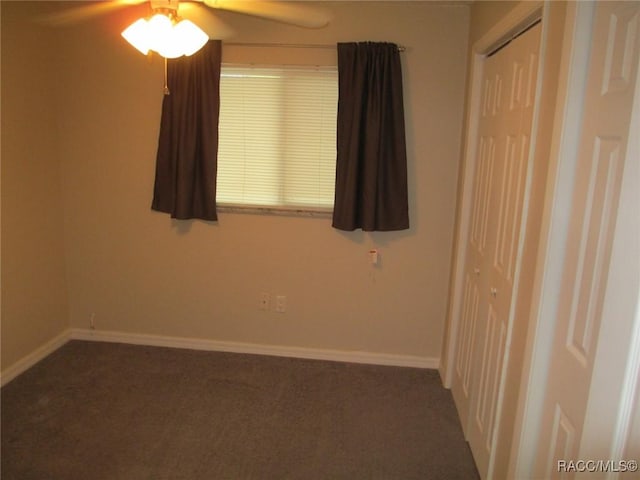 empty room with dark colored carpet and baseboards