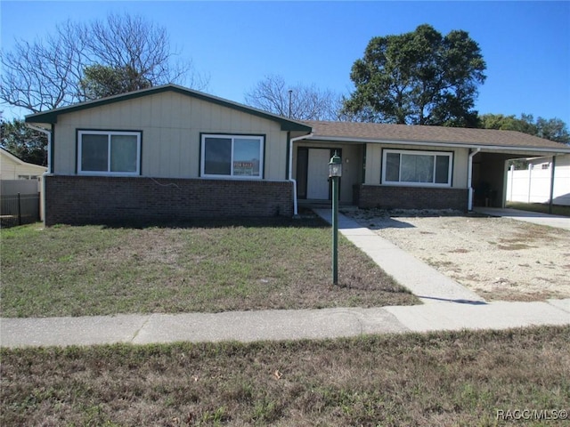 ranch-style home with an attached carport, brick siding, and a front yard