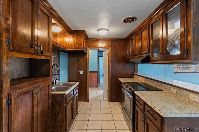 kitchen featuring stainless steel electric stove, wooden walls, sink, and light tile patterned floors