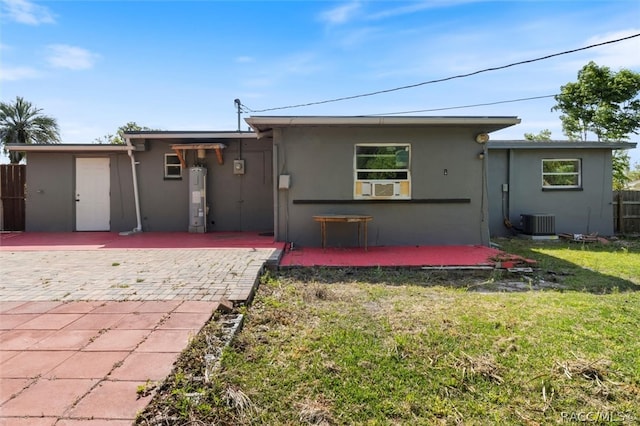 exterior space featuring a lawn, water heater, cooling unit, central AC unit, and a patio area