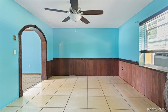 tiled spare room with ceiling fan and wood walls