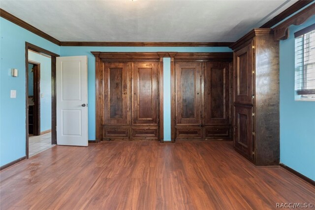 unfurnished bedroom with dark hardwood / wood-style floors and ornamental molding