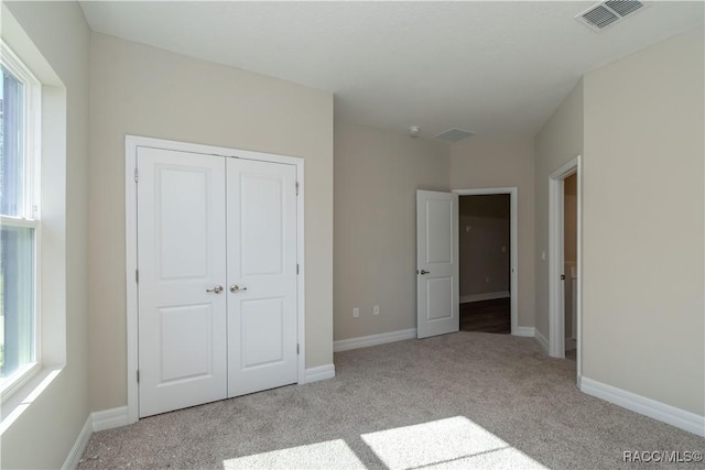 unfurnished bedroom featuring light colored carpet and a closet