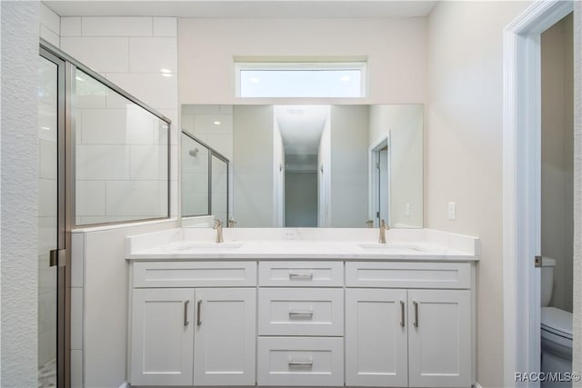 bathroom featuring vanity, a shower with shower door, and toilet